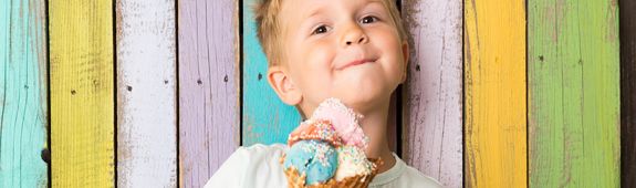 Ein kleiner Junge hält strahlend ein Eis in der Hand. 