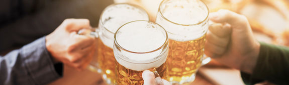 Drei Leute stoßen mit Biergläsern an